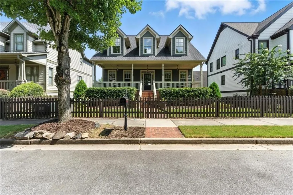 New england style home featuring a porch, roof with shingles, and a fenced front yard