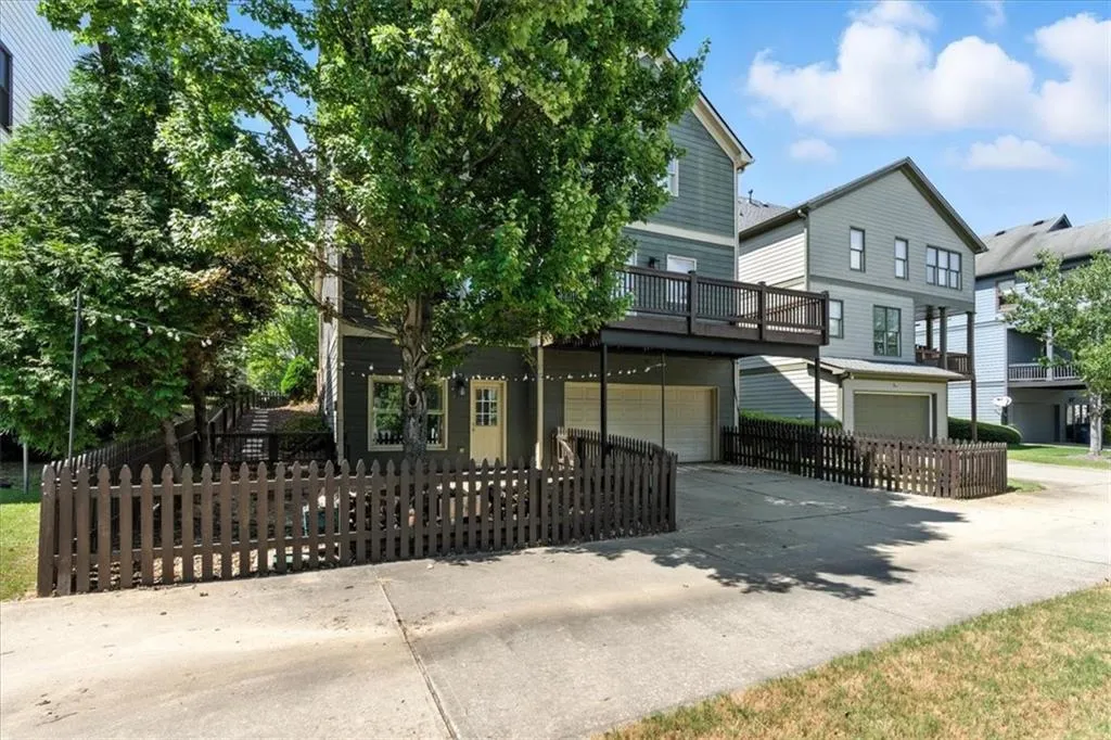 View of property hidden behind natural elements featuring an attached garage, concrete driveway, and a fenced front yard