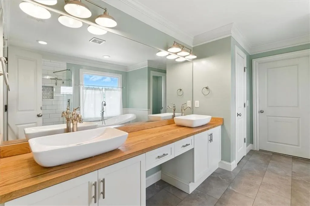 Full bathroom with ornamental molding, double vanity, a freestanding tub, a tile shower, and tile patterned flooring