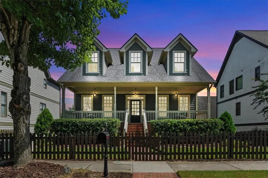 Cape cod-style house with a porch, roof with shingles, and a fenced front yard