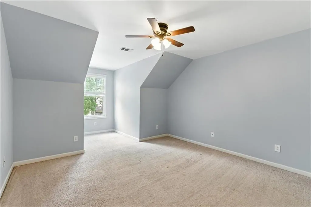 Bonus room featuring carpet, lofted ceiling, and ceiling fan
