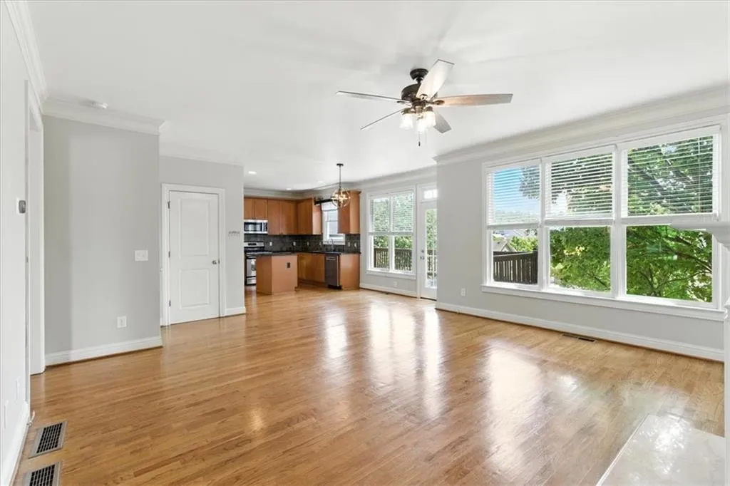 Unfurnished living room with crown molding, light wood finished floors, and ceiling fan