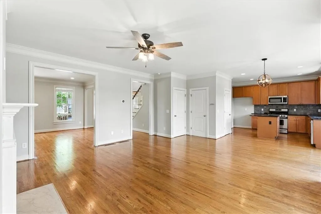 Unfurnished living room with light wood finished floors, crown molding, recessed lighting, ceiling fan, and a chandelier