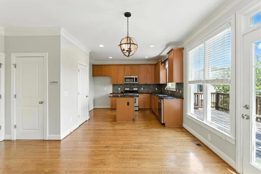 Kitchen featuring dark countertops, backsplash, crown molding, light wood-style flooring, and a chandelier