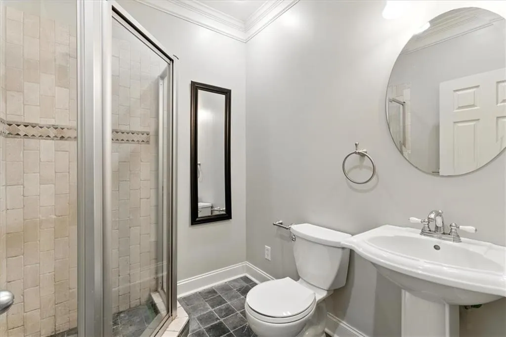 Full bath featuring a shower stall, ornamental molding, and tile patterned floors