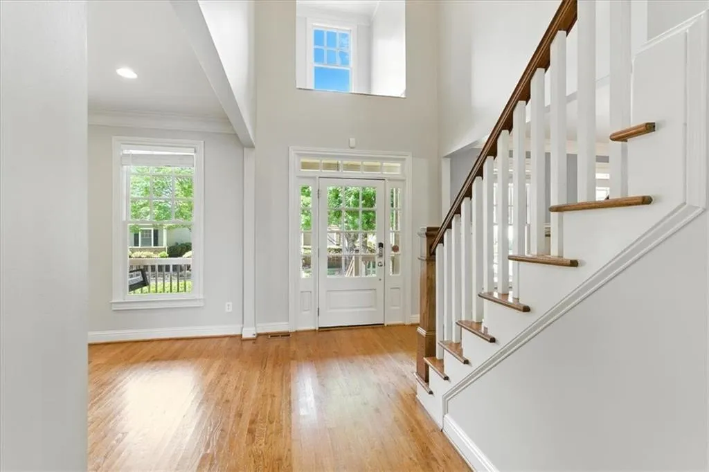 Entryway with healthy amount of natural light, wood finished floors, stairway, and crown molding