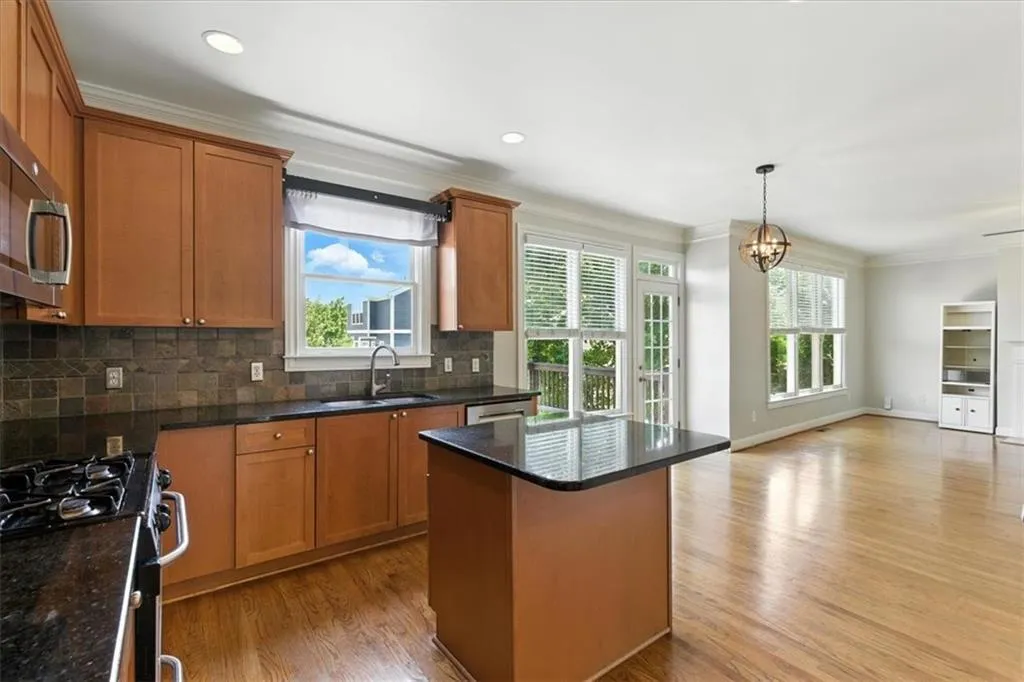 Kitchen featuring ornamental molding, plenty of natural light, backsplash, brown cabinets, and light wood-type flooring