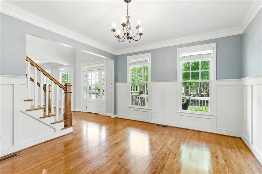 Doorway to outside with a decorative wall, wainscoting, wood finished floors, ornamental molding, and stairs