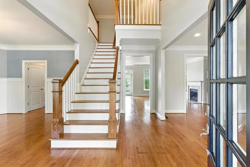 Foyer entrance with ornamental molding, a fireplace, wood finished floors, and stairs