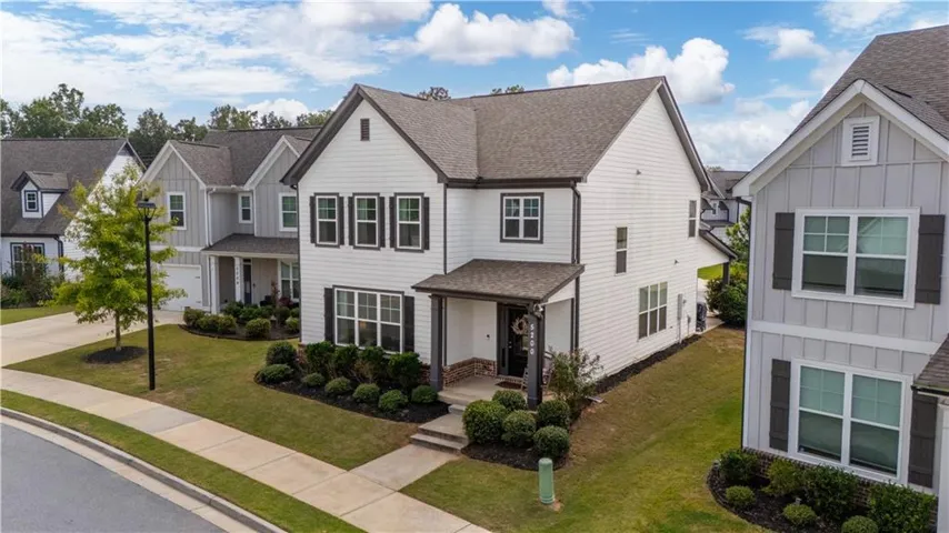 Two-story residence featuring white siding, dark shutters, and a covered front entry with stone accents