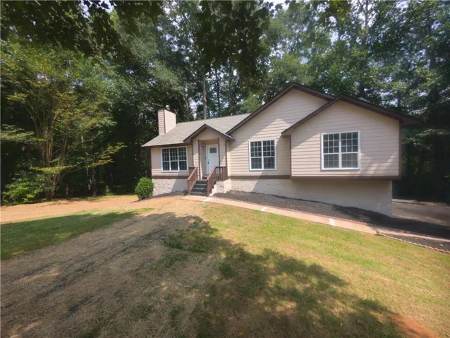 Siding exterior with multiple windows, leading to a front entry with wooden steps and railings