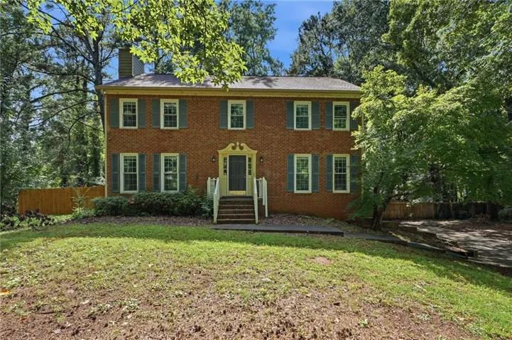 Brick two-story colonial-style residence featuring a prominent front entrance with decorative millwork and a transom window