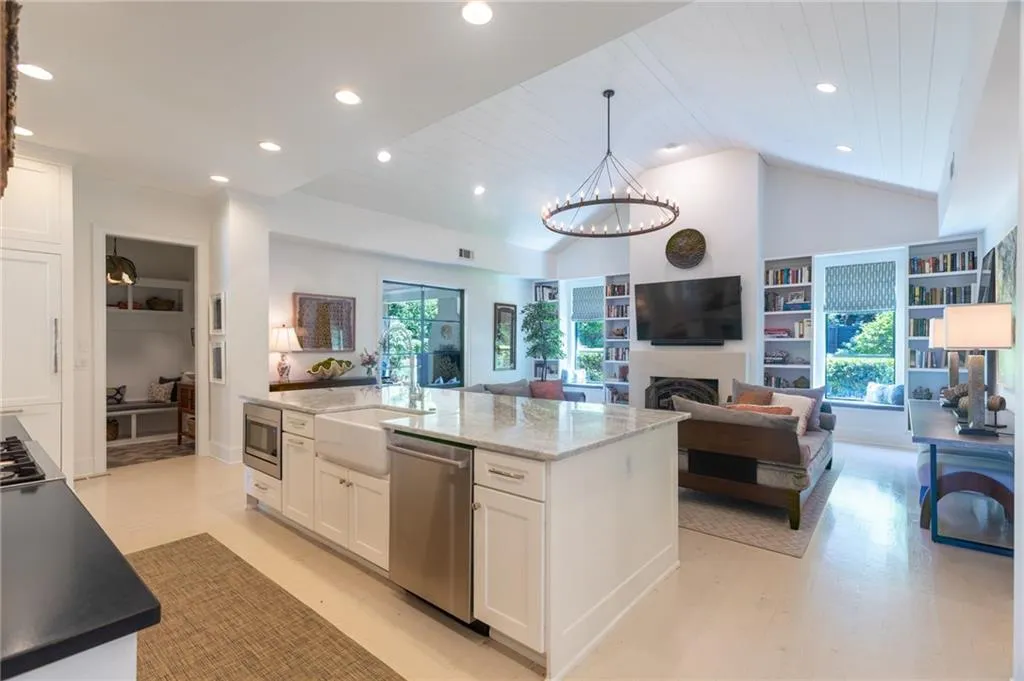 Kitchen with appliances with stainless steel finishes, white cabinets, a kitchen island, and light stone counters