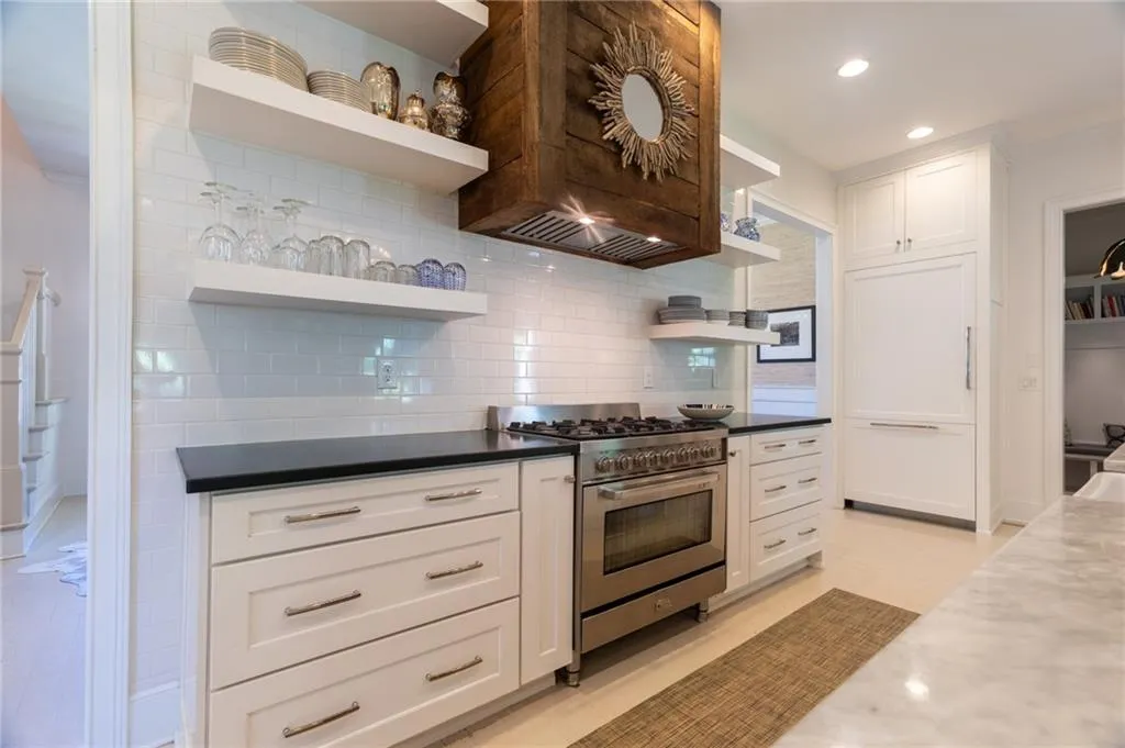 Kitchen with white cabinets, high end stove, and tasteful backsplash