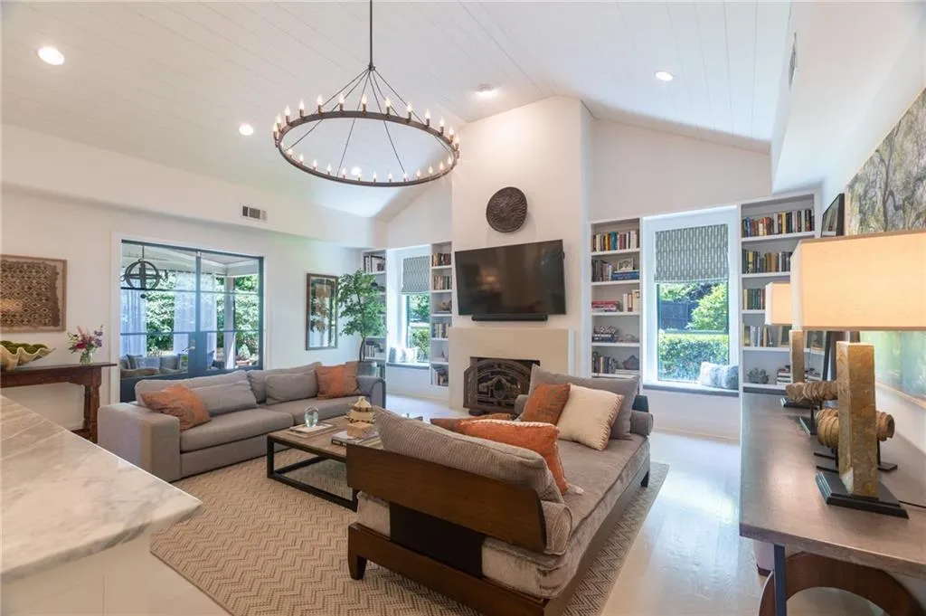 Living room with a notable chandelier, high vaulted ceiling, built in shelves, and hardwood / wood-style flooring