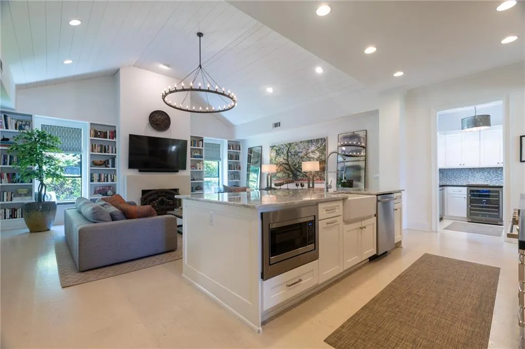 Kitchen featuring wine cooler, tasteful backsplash, an island with sink, stainless steel appliances, and white cabinetry