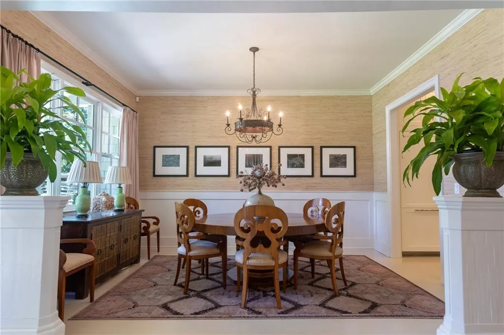 Dining area with tile floors, ornamental molding, decorative columns, and an inviting chandelier