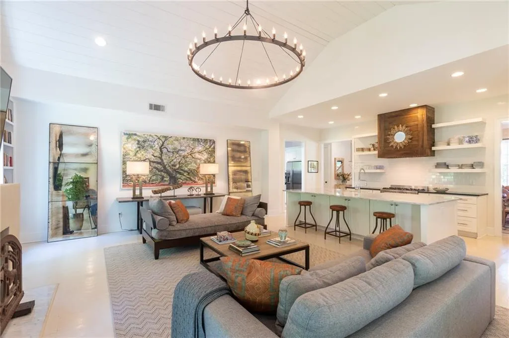 Living room featuring high vaulted ceiling, sink, light tile floors, and a chandelier