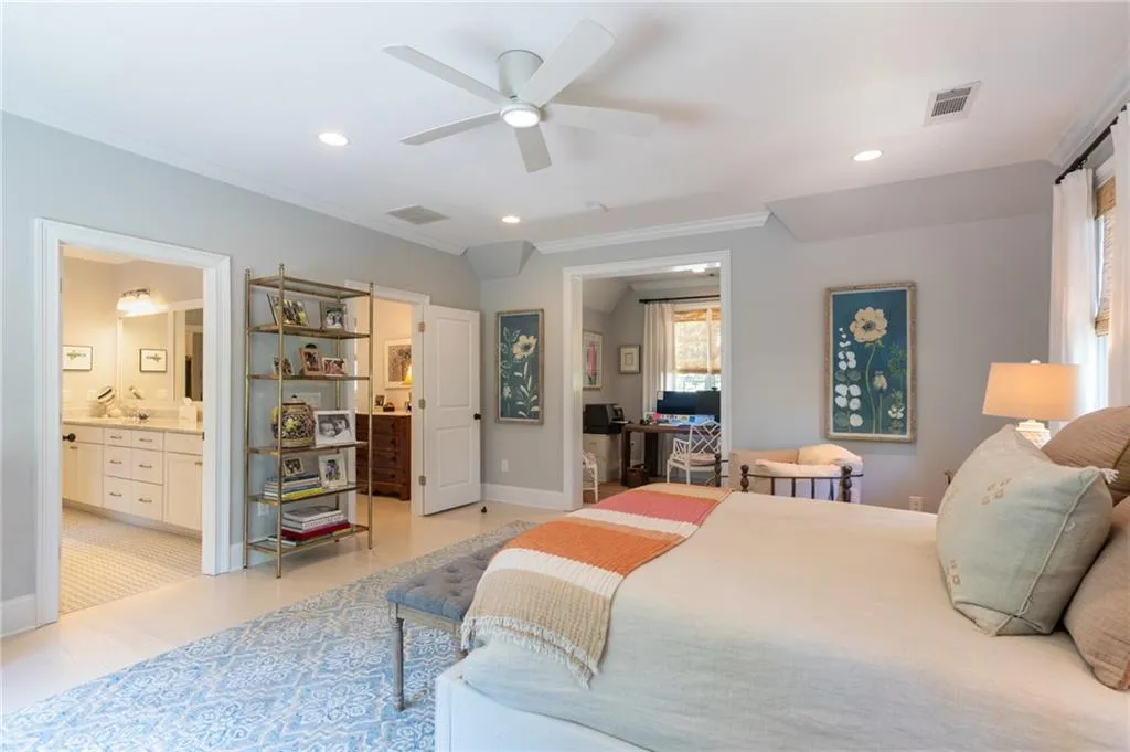 Tiled bedroom with ceiling fan, connected bathroom, and ornamental molding