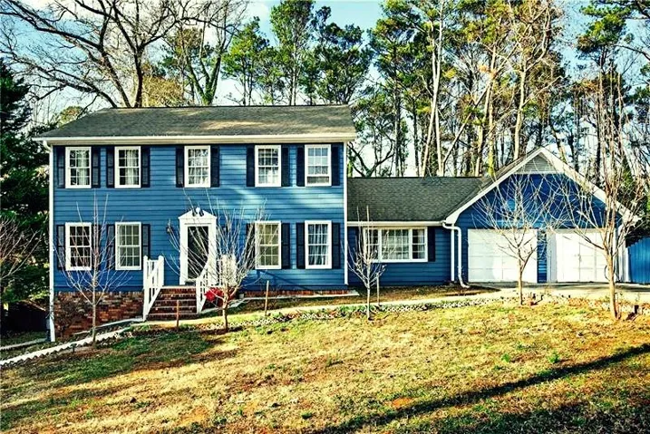 Two-story residence featuring blue siding, white window trim, and dark shutters