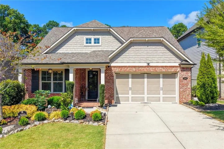 Brick and shake siding exterior featuring a covered entry, decorative shutters, and an attached two-car garage