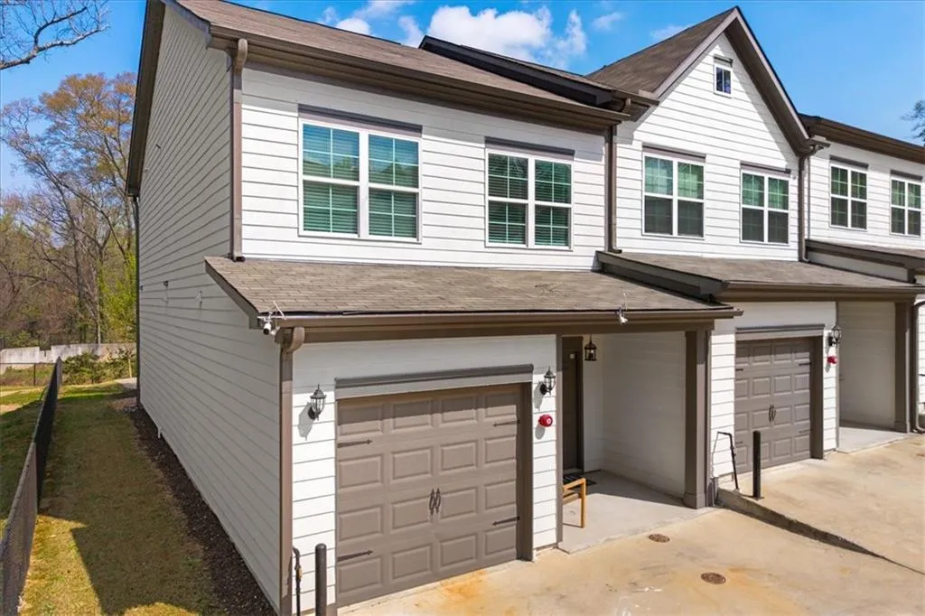 Traditional home featuring an attached garage, roof with shingles, and driveway