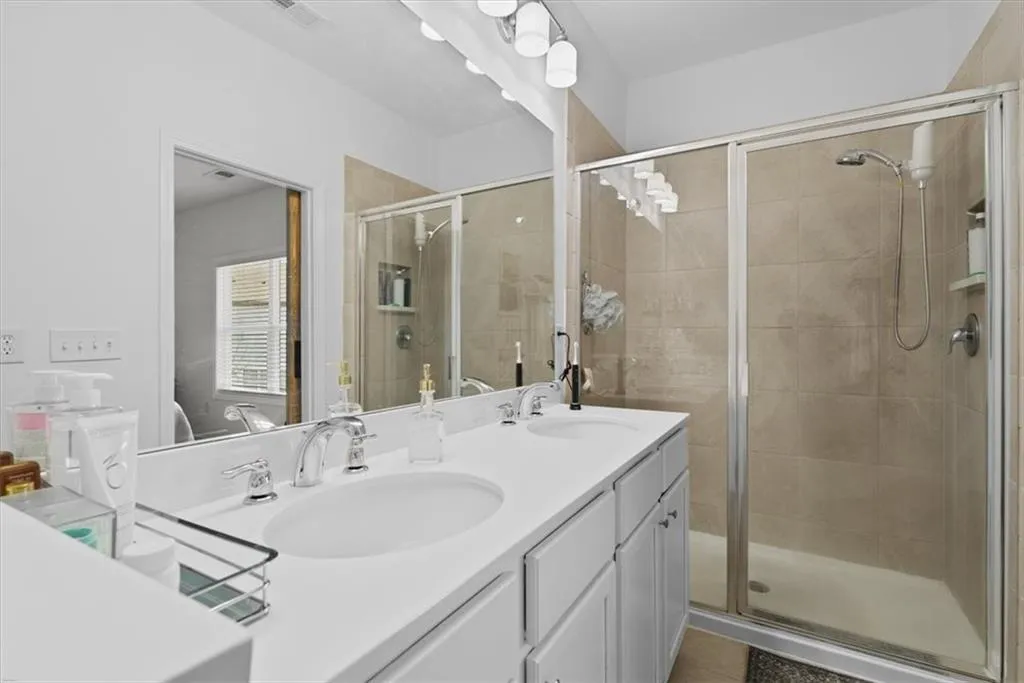 Full bathroom featuring double vanity and a stall shower