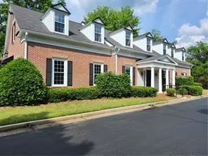 Brick exterior with dormer windows, architectural shingles, and a columned entry