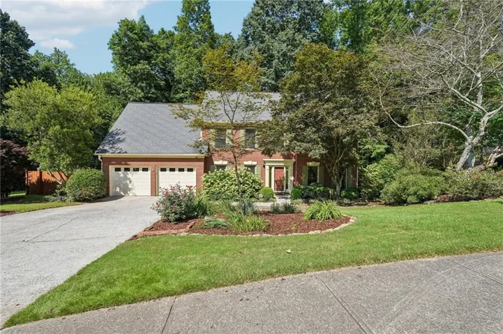 Brick exterior with a shingled roof, two-car garage, and a concrete driveway