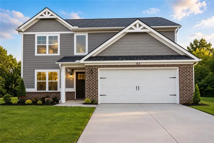 Modern two-story residence featuring a two-car garage, gray horizontal siding, brick accents, and a dark shingle roof