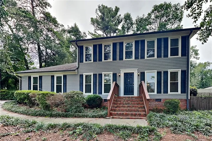 Two-story residence featuring grey horizontal siding and dark blue window shutters