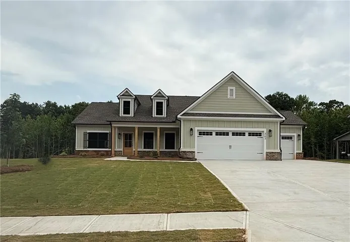 Elegant farmhouse-style residence featuring a symmetrical facade with dual dormers, cream-colored siding with brick accents, and a two-car garage with paneled doors