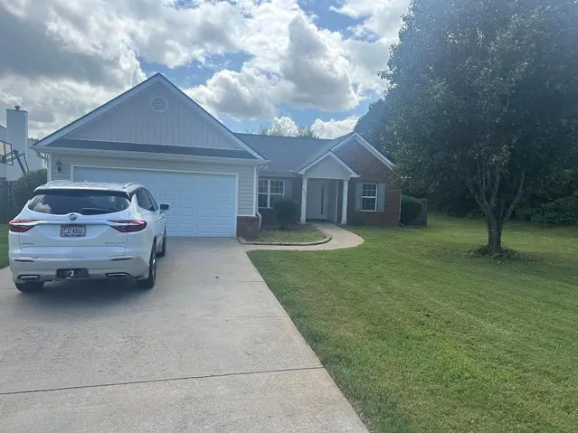 Ranch-style residence featuring a brick and siding exterior, an attached two-car garage, a concrete driveway, and a front porch with columns
