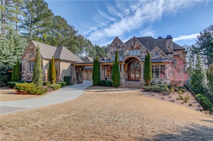 Tudor house with stone siding, a chimney, french doors, and a front yard