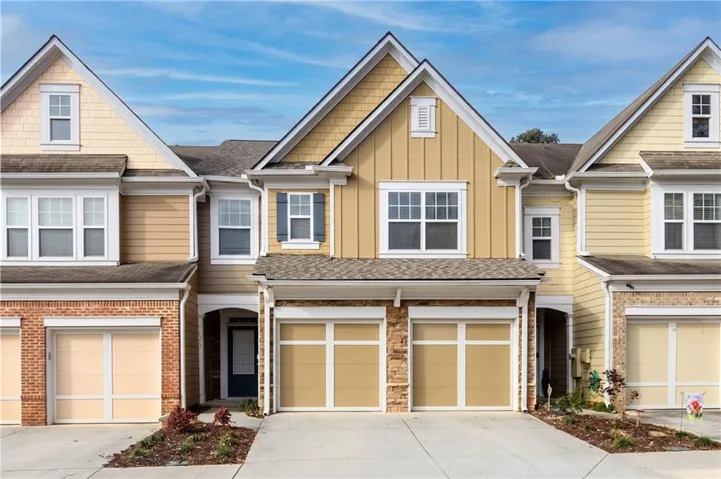 Multi-level townhome with an attached two-car garage, stone façade, and gabled rooflines