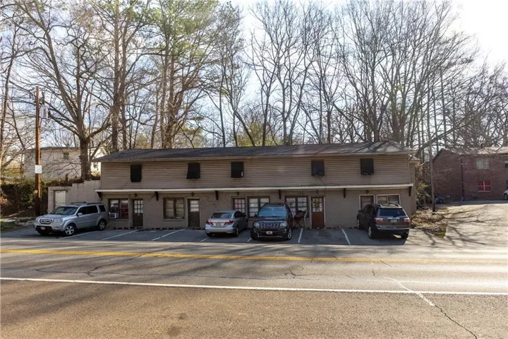 View of front facade with uncovered parking and brick siding