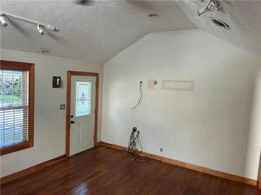 Foyer entrance featuring lofted ceiling, dark wood-style flooring, a textured ceiling, and rail lighting
