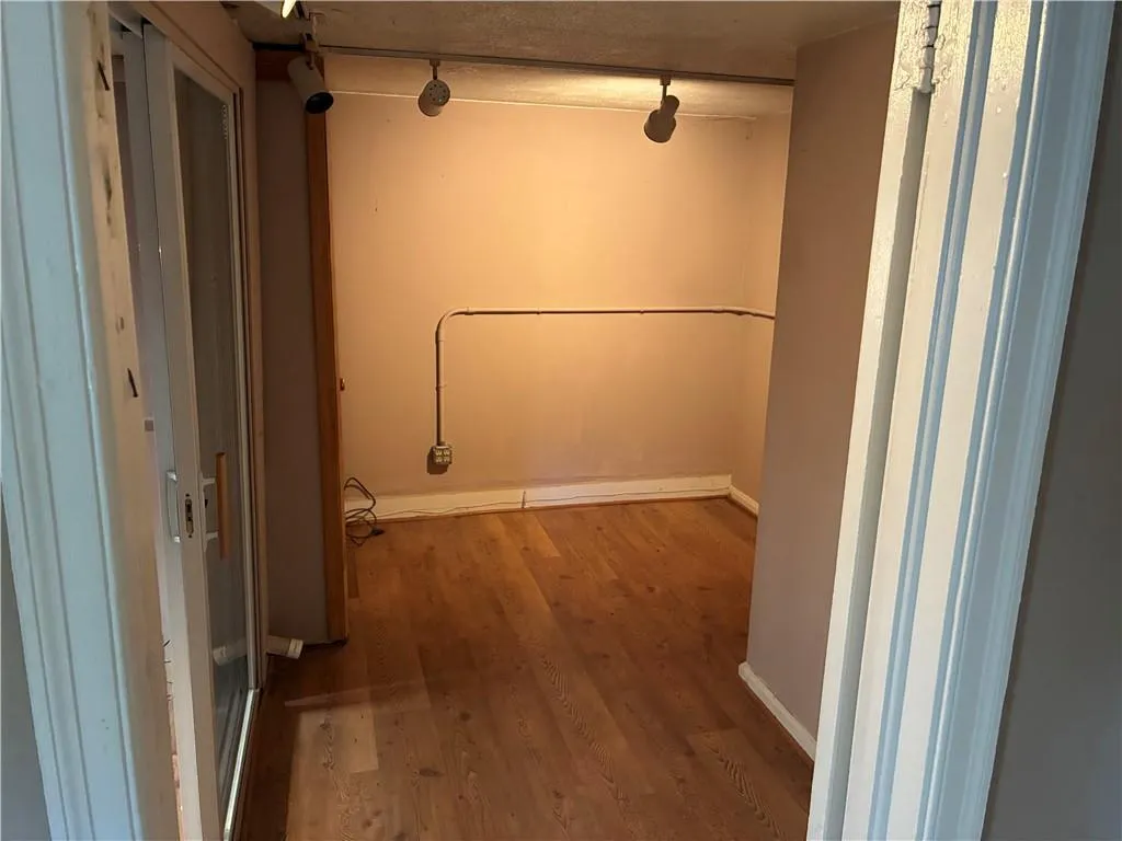 Hall featuring wood finished floors and track lighting