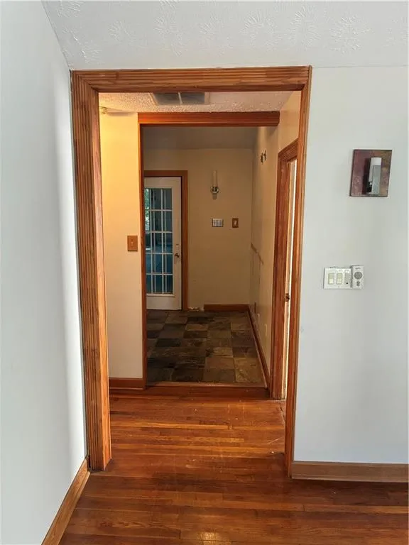 Hallway with dark wood finished floors and a textured ceiling