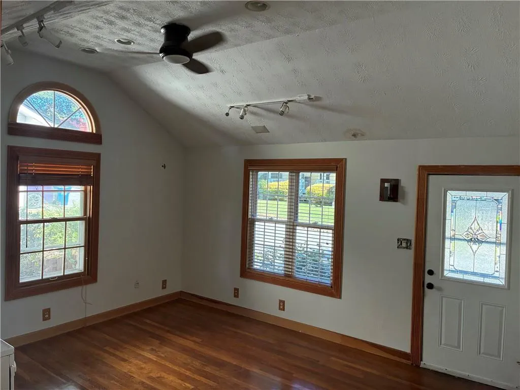 Foyer entrance with rail lighting, vaulted ceiling, dark wood-style floors, a ceiling fan, and a textured ceiling