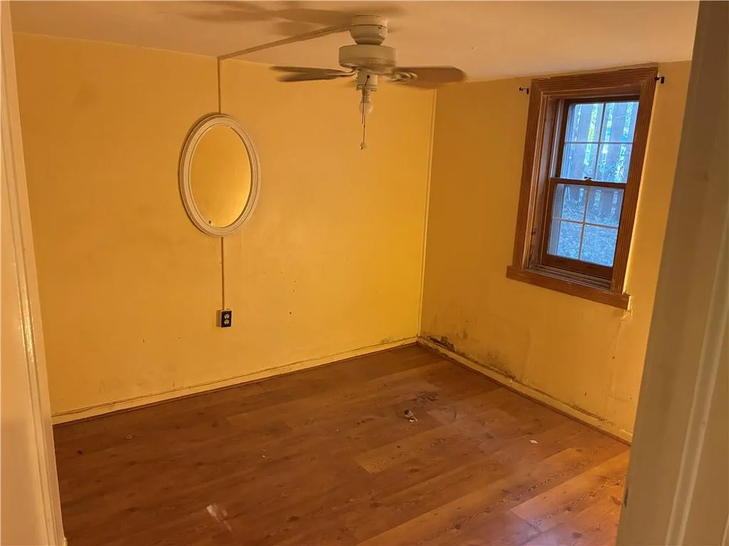 Empty room with wood finished floors and ceiling fan