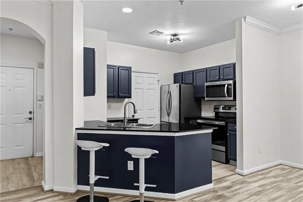Kitchen featuring dark countertops, a kitchen bar, stainless steel appliances, a peninsula, and light wood-style floors