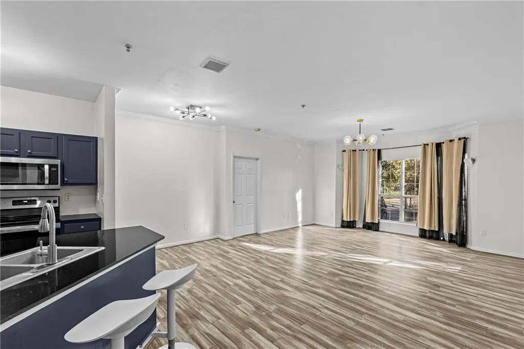 Kitchen featuring dark countertops, light wood-style flooring, stainless steel appliances, blue cabinets, and suspended lighting