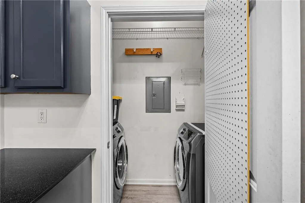 Laundry area featuring electric panel, washer and clothes dryer, and light wood-style flooring