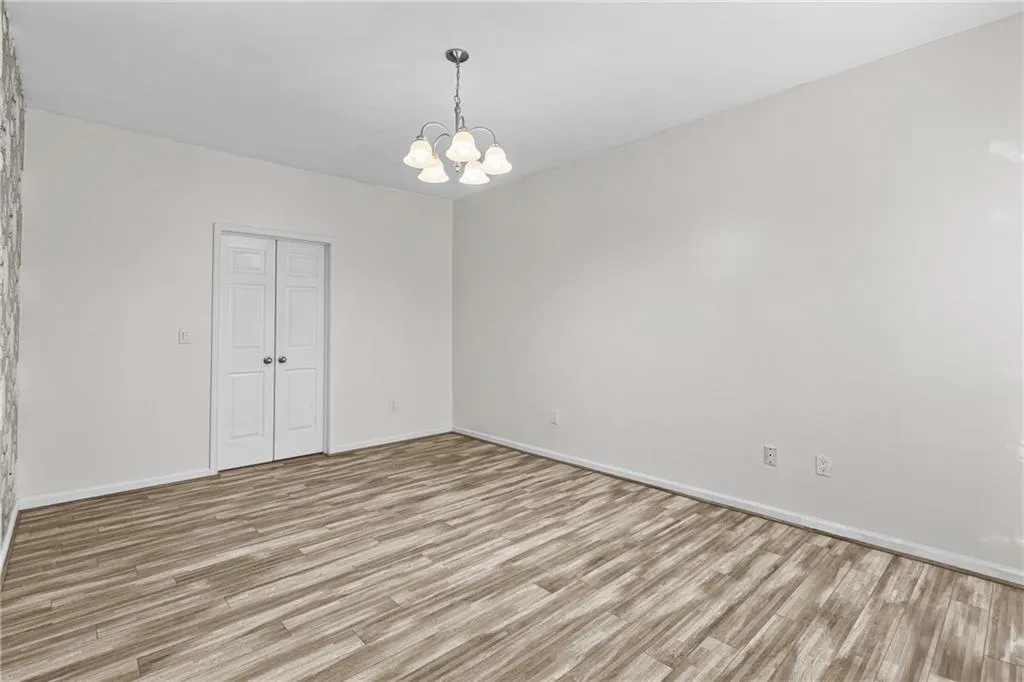 Empty room with suspended lighting and light wood finished floors