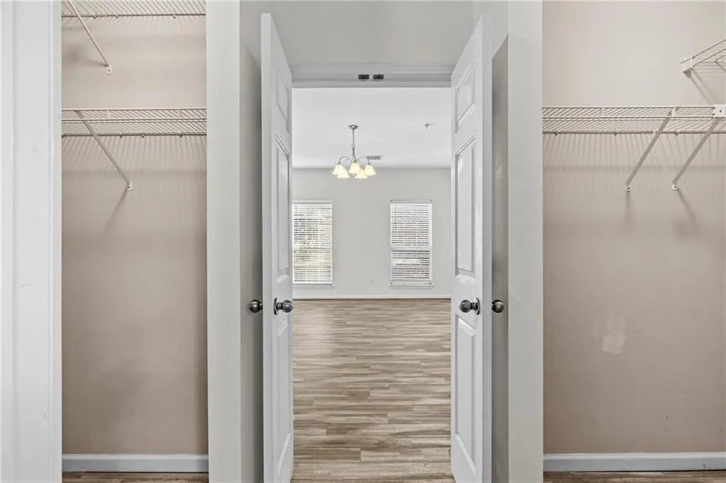 Walk in closet featuring light wood finished floors and suspended lighting