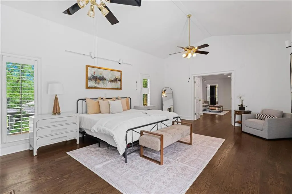 oversized primary suite with high, vaulted ceilings and natural light spilling in through the floor length windows