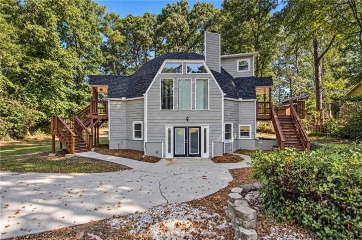 Gable roofline exterior with gray siding, multiple windows, double entry doors, and two exterior staircases leading to upper-level balconies