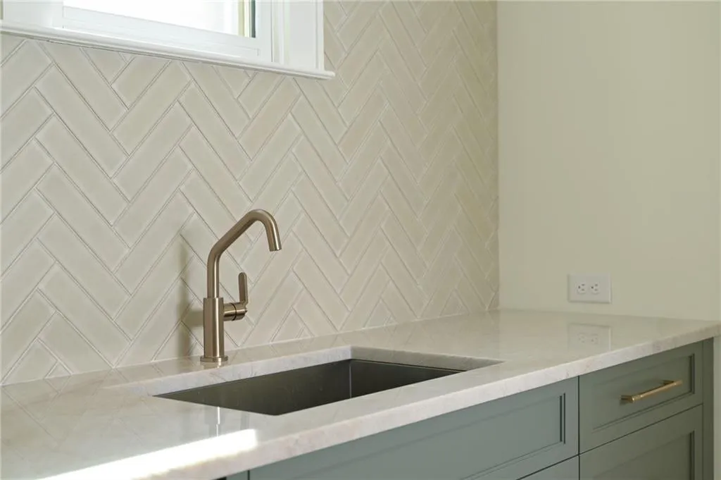 Details featuring light stone countertops, sink, and backsplash