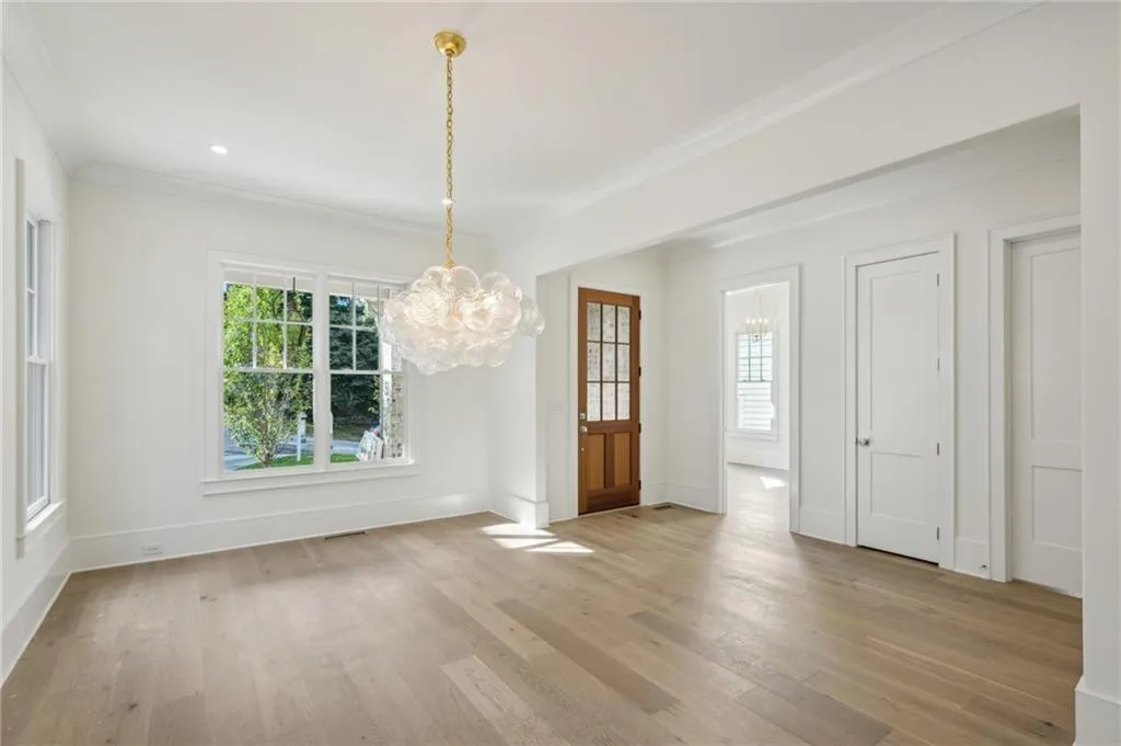 Unfurnished dining area with an inviting chandelier, crown molding, and light hardwood / wood-style floors